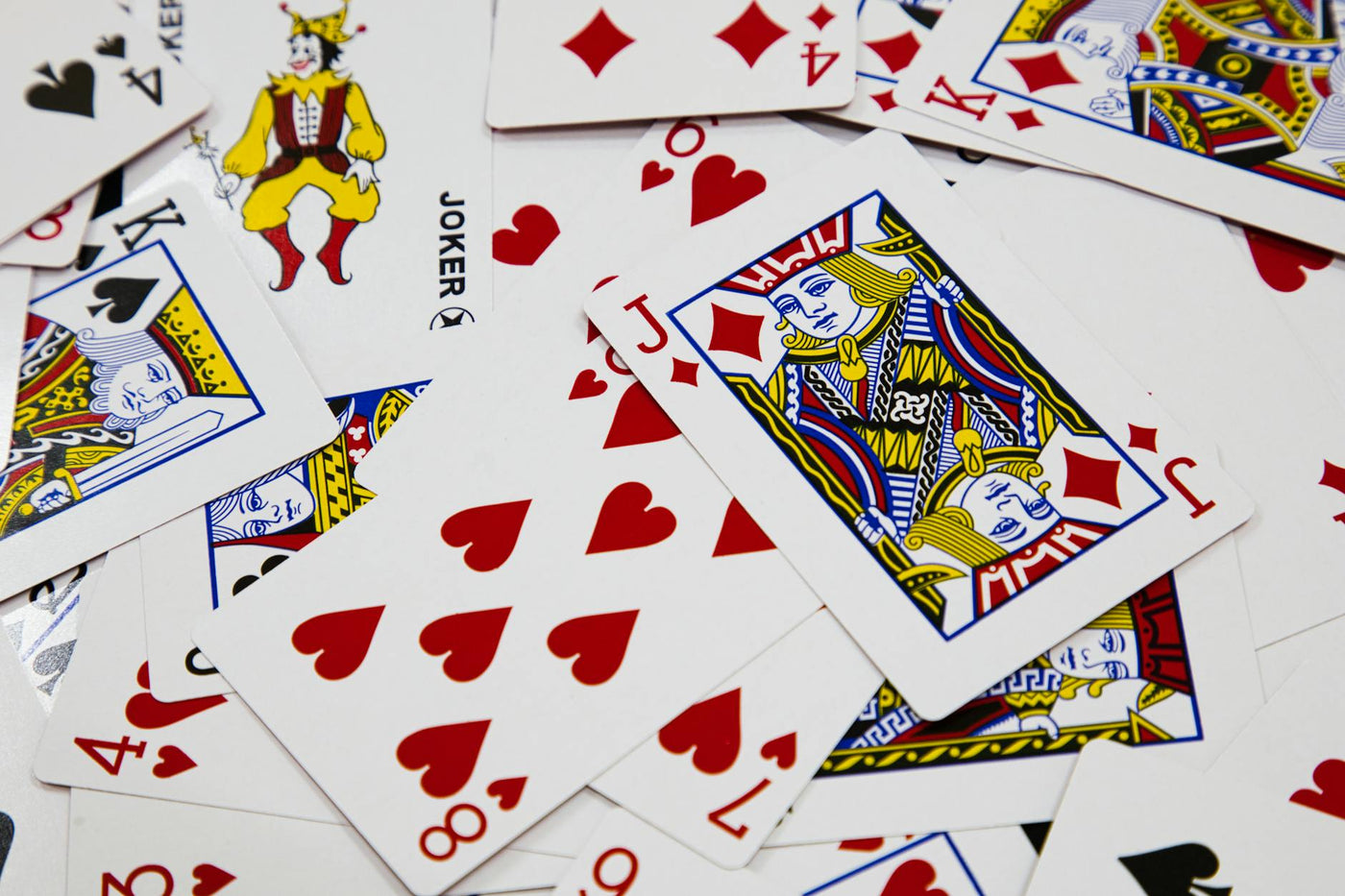 A vibrant arrangement of playing cards depicting various suits and a joker in a dynamic composition.