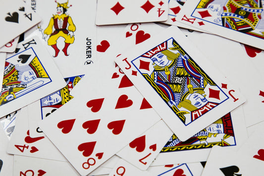 A vibrant arrangement of playing cards depicting various suits and a joker in a dynamic composition.